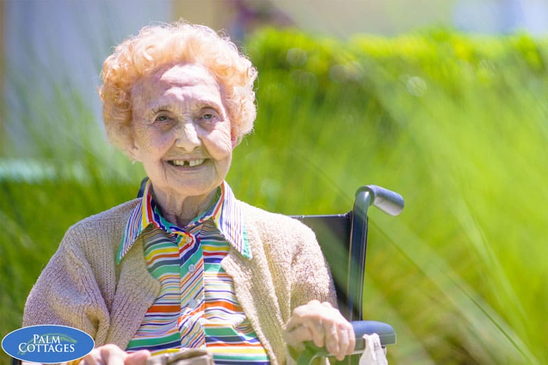 elderly female memory care facility resident sitting outside, enjoying the warm weather